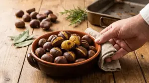 Ciotola di castagne arrosto su tavolo rustico con una mano che la serve