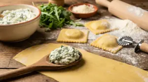 Preparazione dei ravioli fatti in casa con ripieno cremoso di ricotta ed erbe su sfoglia fresca infarinata